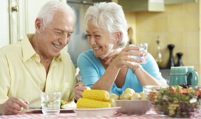 Older couple eating vegetables in a bright room